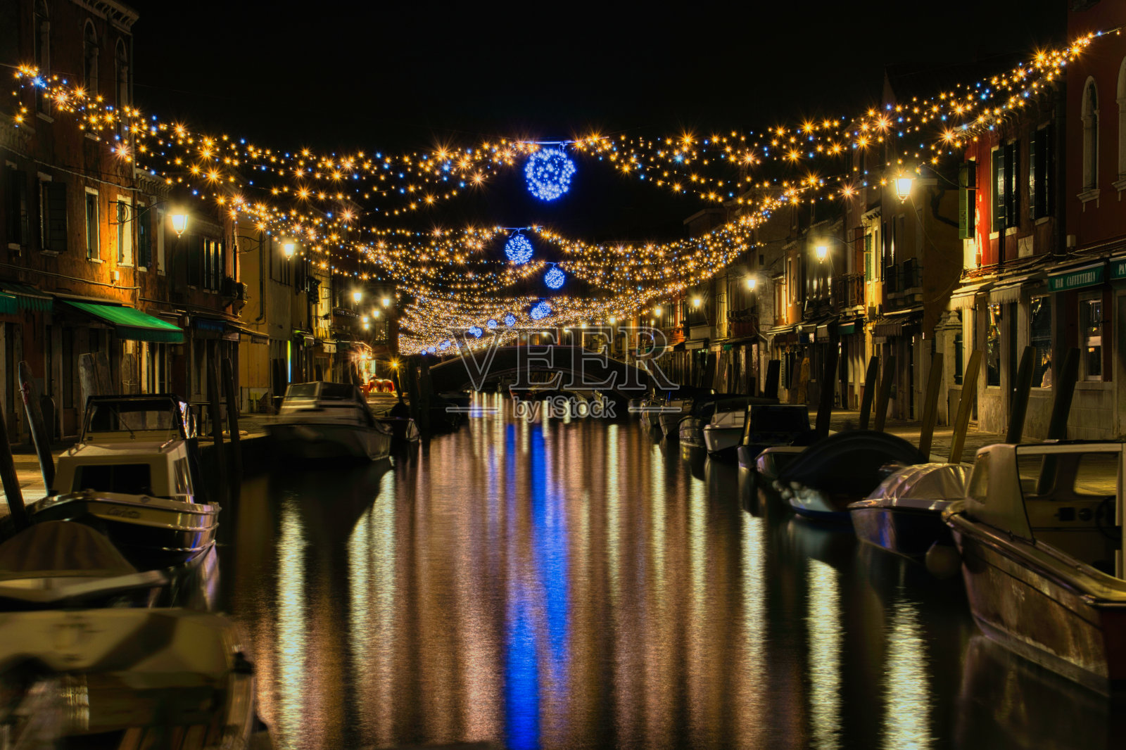 灯火通明的船只漂浮在桥上，桥上挂着串灯照片摄影图片