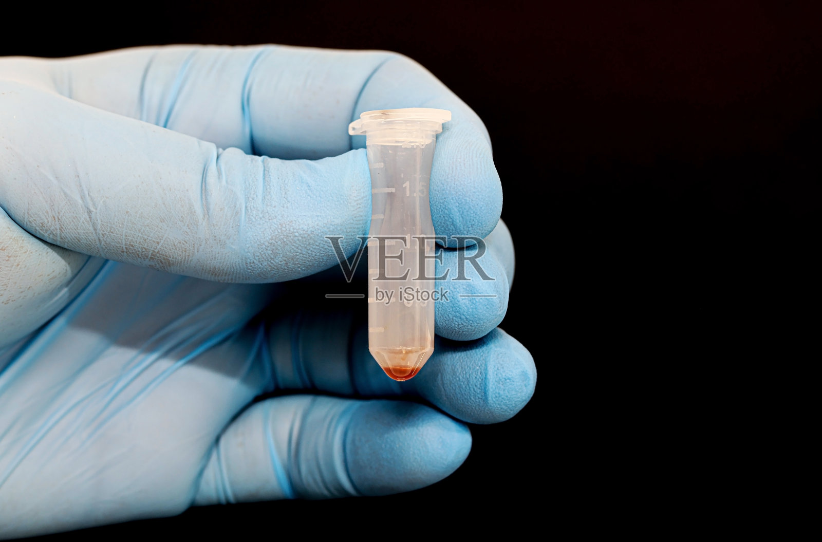 科学家或医生手戴手套，拿着装有红色生物样本的试管照片摄影图片