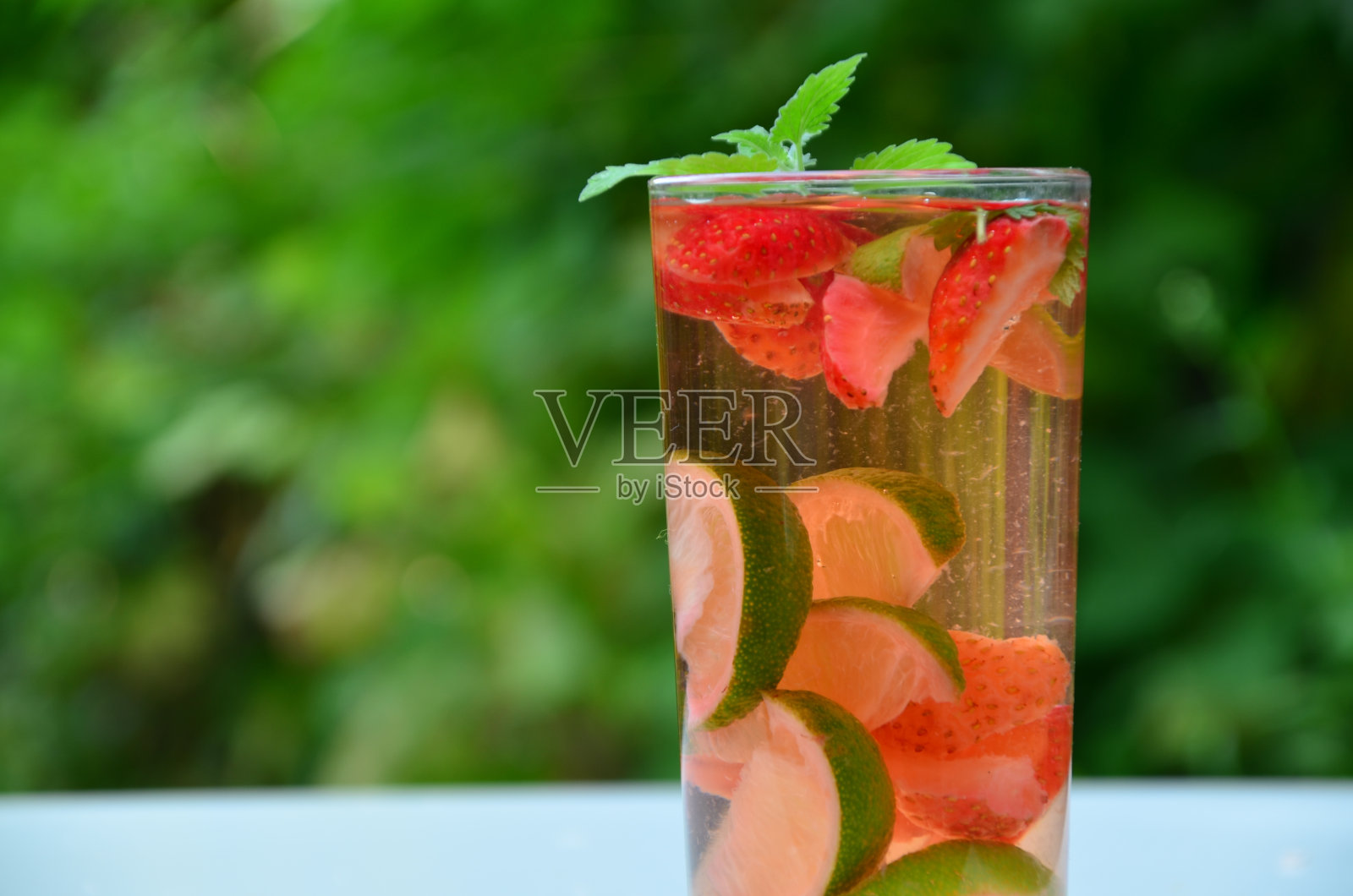夏日清凉的草莓饮料，木桌上有杯子。新鲜草莓莫吉托饮料。鸡尾酒或无酒精鸡尾酒用新鲜的薄荷。夏天排毒喝酒，节食减肥照片摄影图片