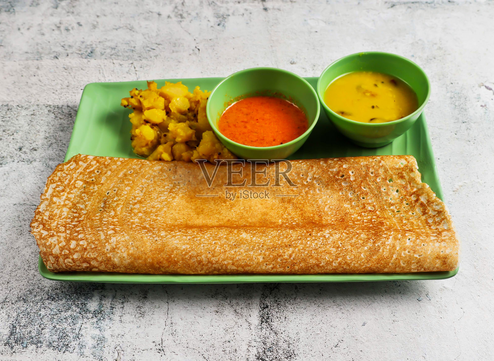 马沙拉(Masala)或马沙拉(Masala) dosa，配肉汁酱和土豆布加，盛在盘子里，这是新加坡食物的灰色背景侧视图照片摄影图片