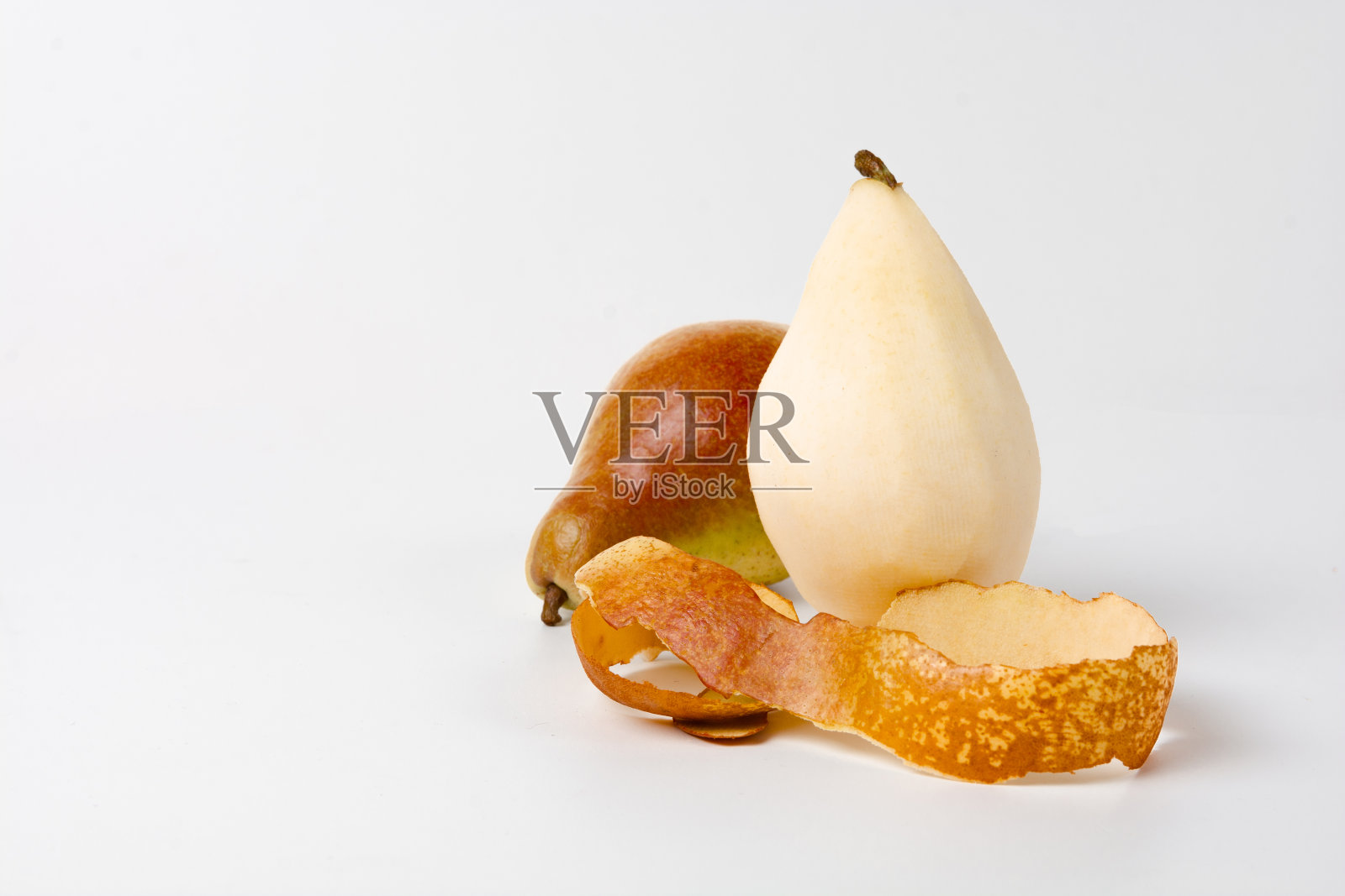 两个梨的特写图像，一个是棕色的皮，一个是黄色的皮，躺在白色的表面上，前面是棕色梨的皮照片摄影图片