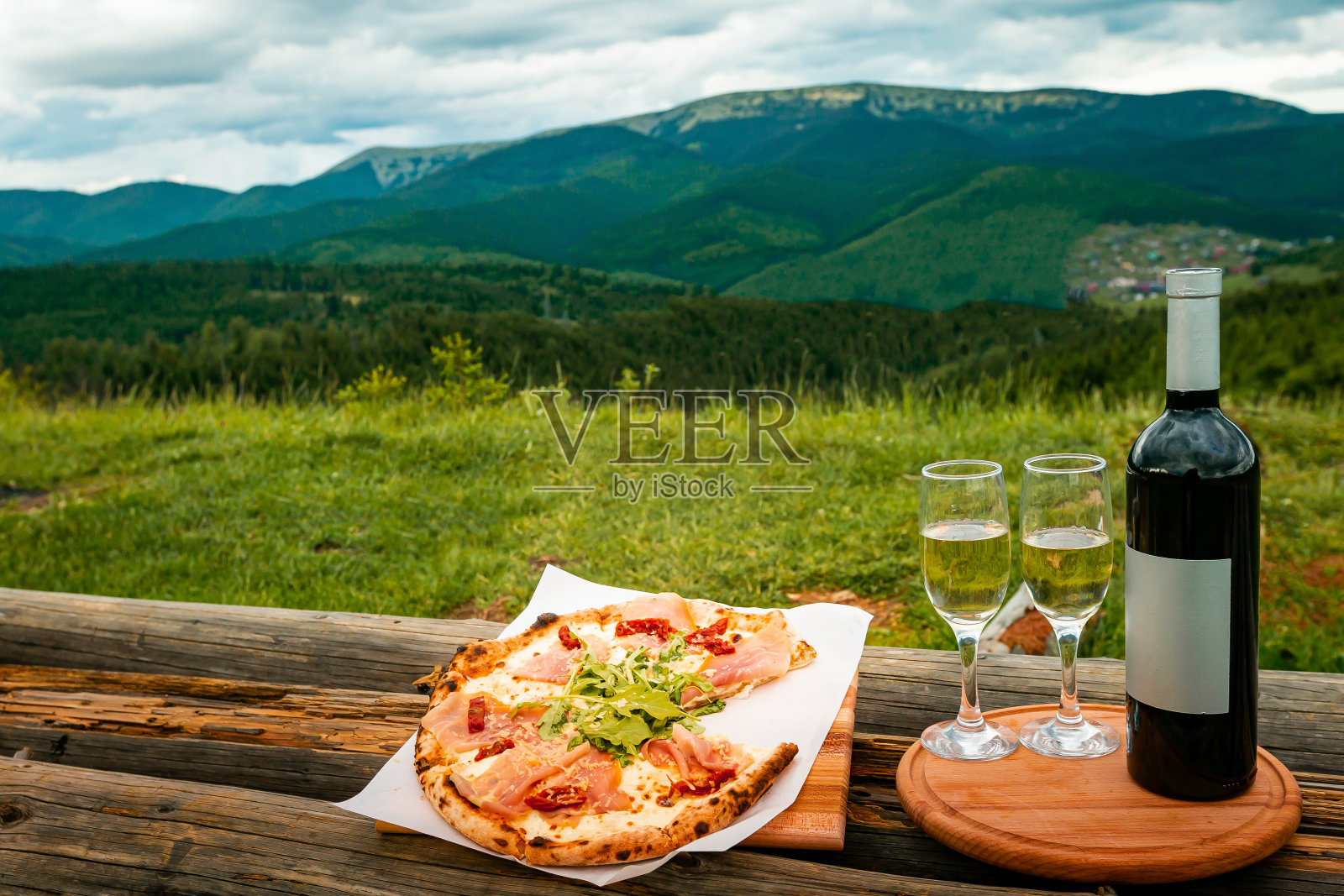 在户外的山上吃晚餐。在一个美丽的地方，披萨和红酒摆在桌子上。照片摄影图片