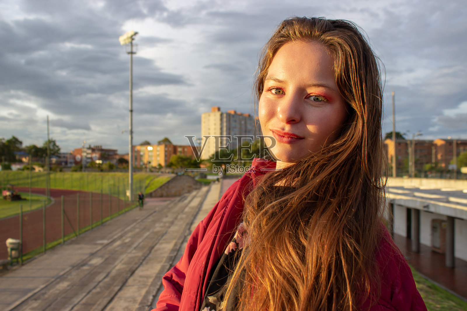 美丽的年轻女子在日落时分穿着夹克，阳光照在她的脸上照片摄影图片