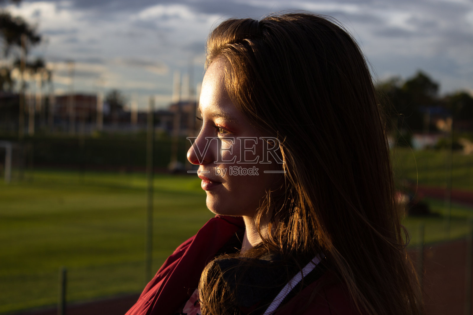 美丽的年轻女子在日落时分穿着夹克，阳光照在她的脸上照片摄影图片