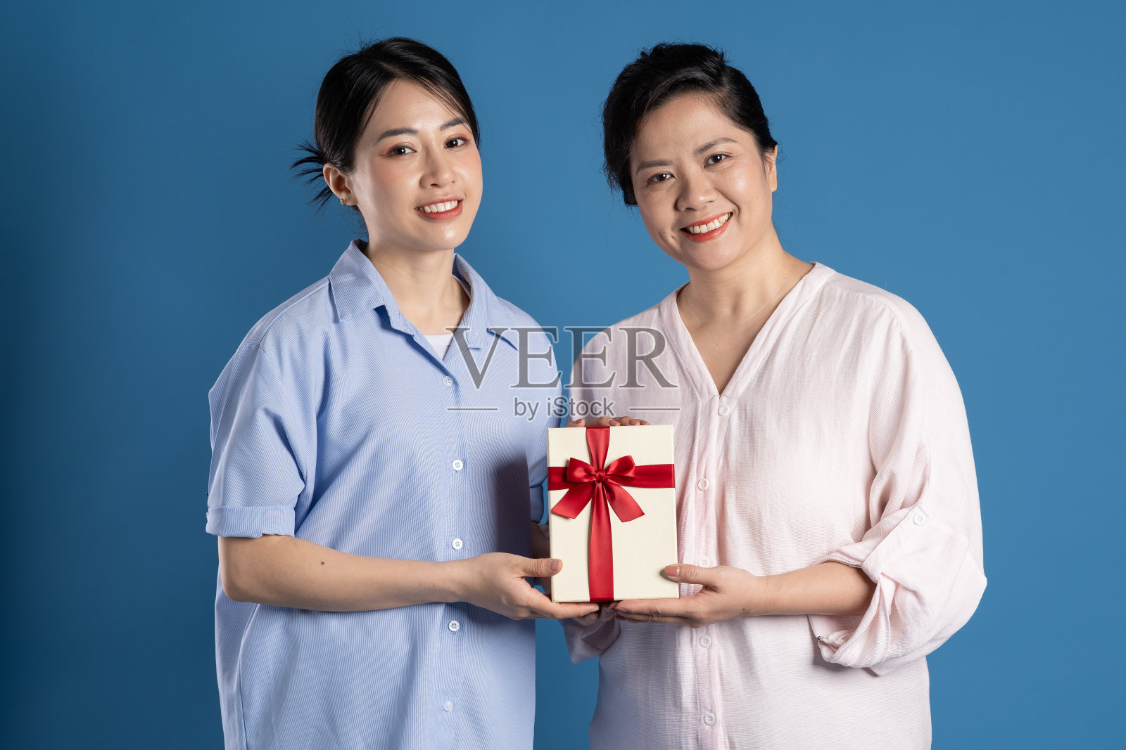 图为一位亚洲母亲和孩子在蓝色背景上摆姿势照片摄影图片