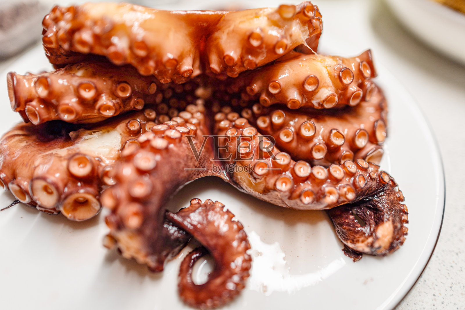 从锅中取出煮熟的红章鱼。照片摄影图片