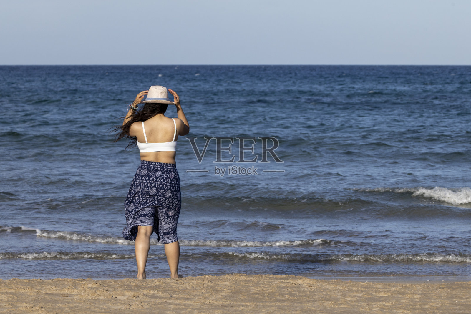 沙滩上戴着帽子的女孩。照片摄影图片