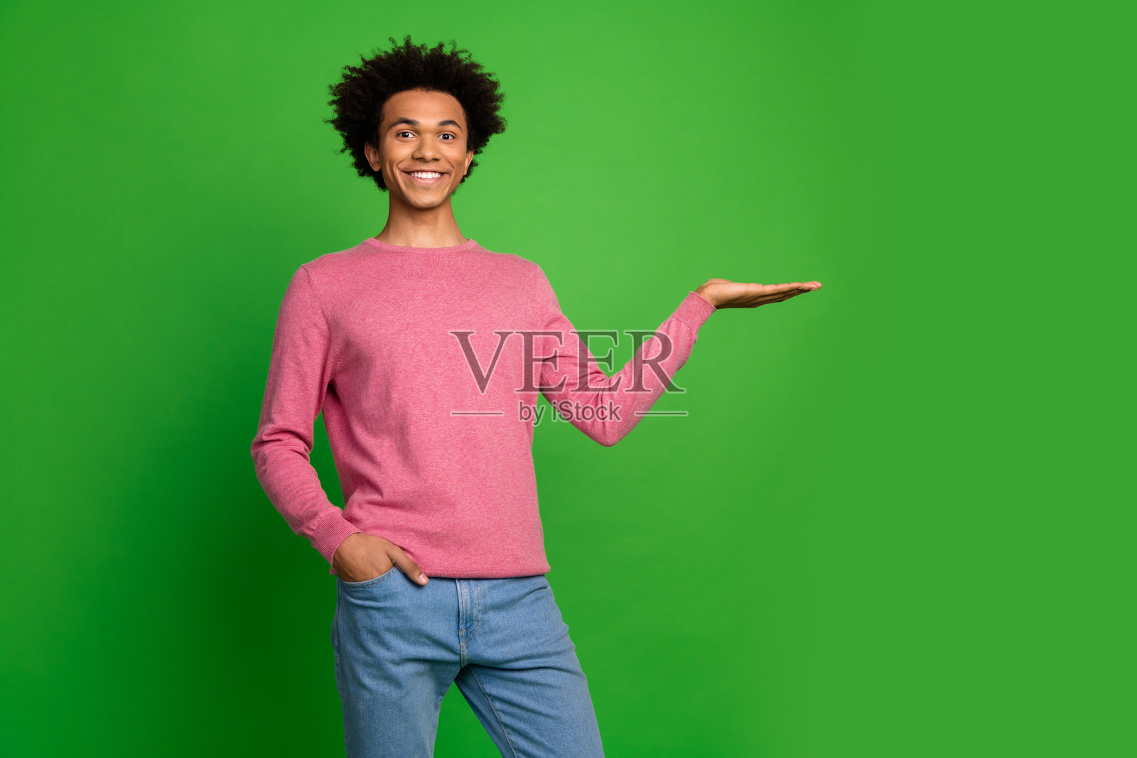 照片中的开朗积极的家伙穿着粉红色的套头衫，显示手臂空白的空间孤立的绿色背景照片摄影图片