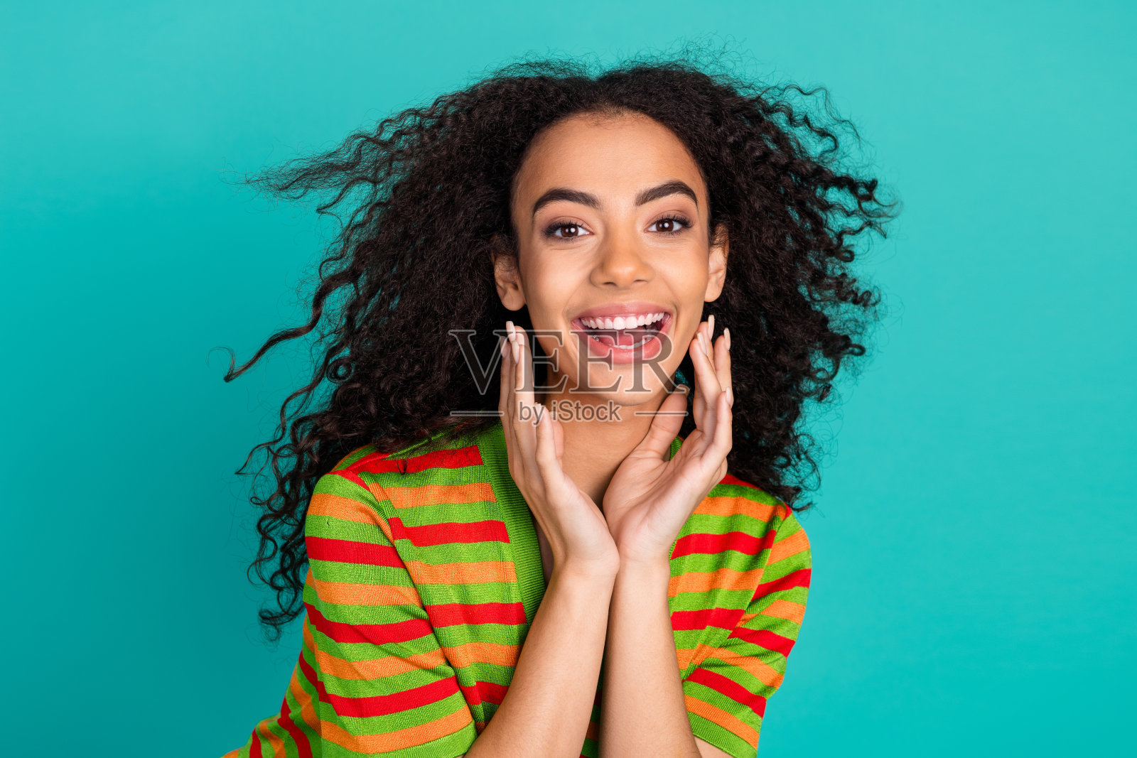 照片肖像可爱的年轻女士飘动的头发微笑穿着时尚的条纹服装孤立的青色背景照片摄影图片