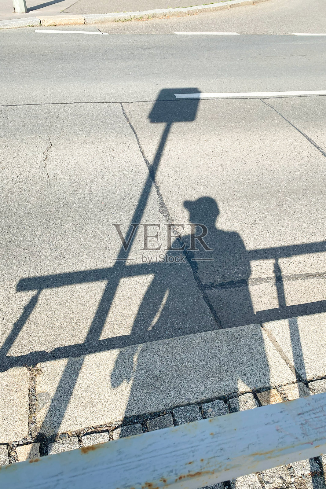 在一个阳光明媚的日子里，男人的影子投射在公交车站上，象征着等待公共交通。照片摄影图片