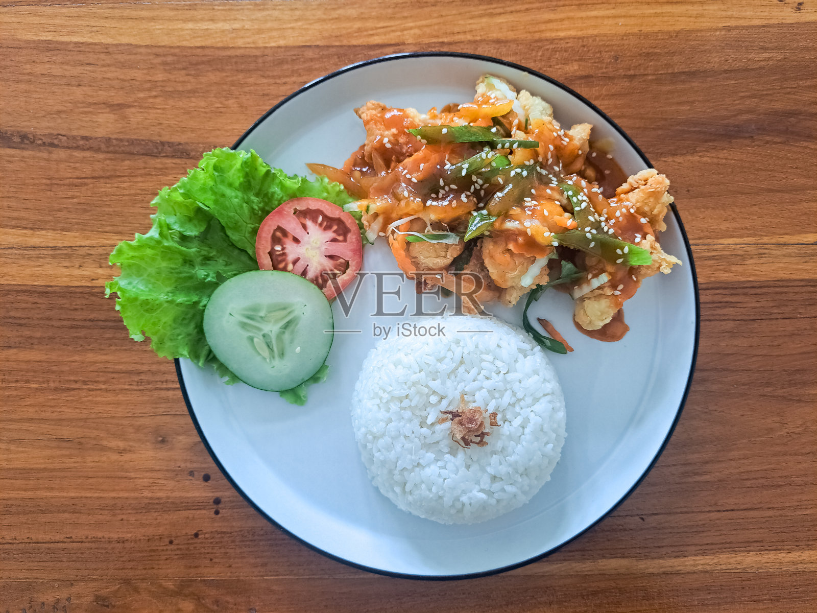 糖醋鸡配辣酱，芝麻，切碎的香葱，大蒜，黄瓜，西红柿，生菜和炒洋葱。食品菜单。前视图。照片摄影图片