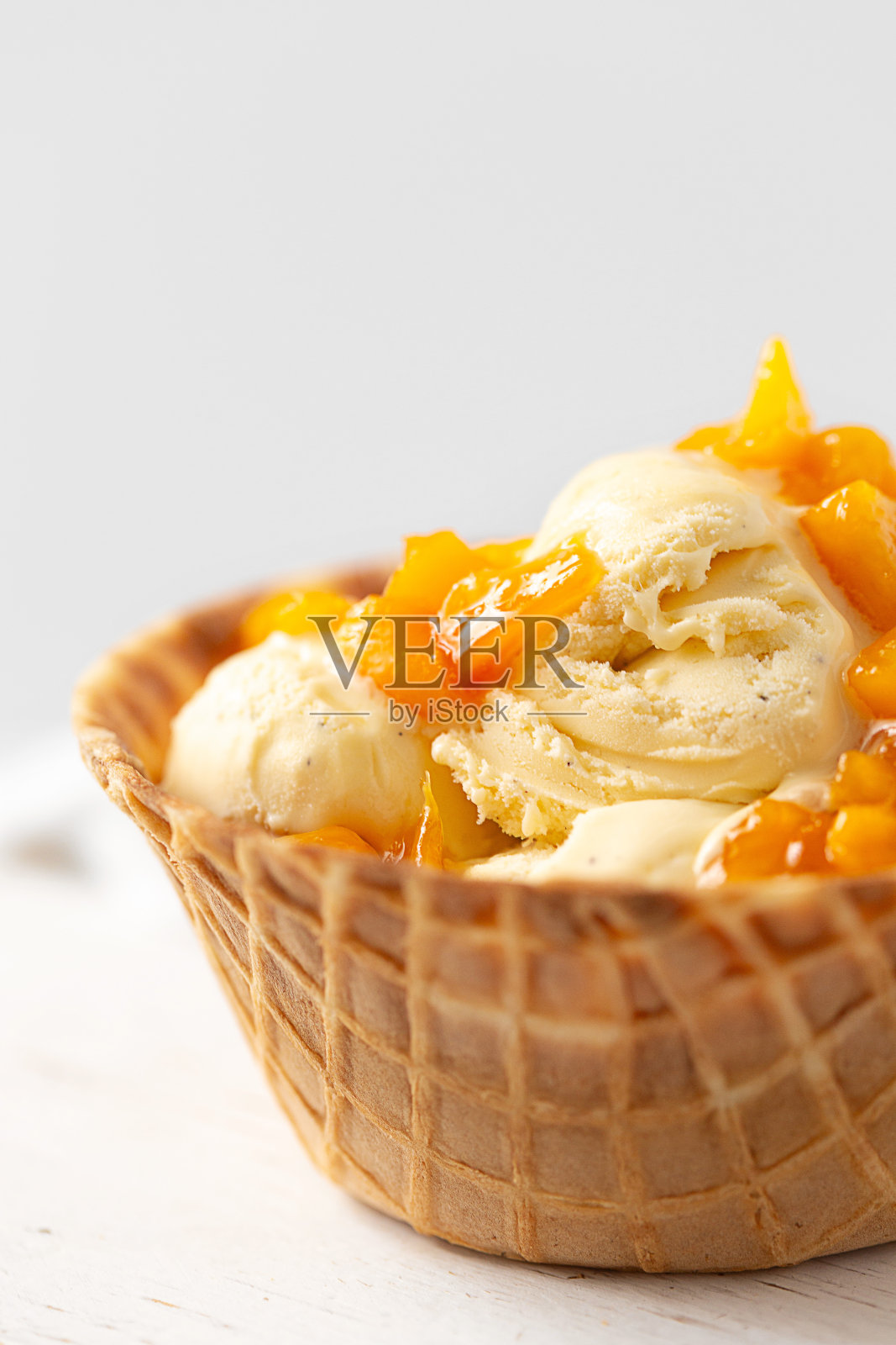 香草冰淇淋在华夫饼碗顶部与新鲜桃子在白色背景照片摄影图片