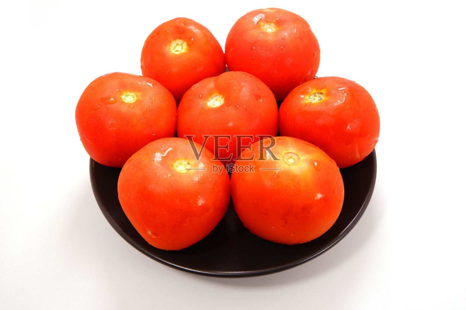 白色背景上黑色盘子里的新鲜番茄特写照片摄影图片
