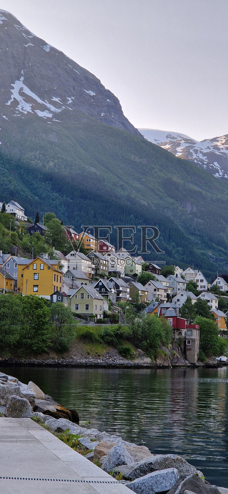挪威奥达，湖岸的山脚下的小山上的彩色房屋的垂直视图照片摄影图片