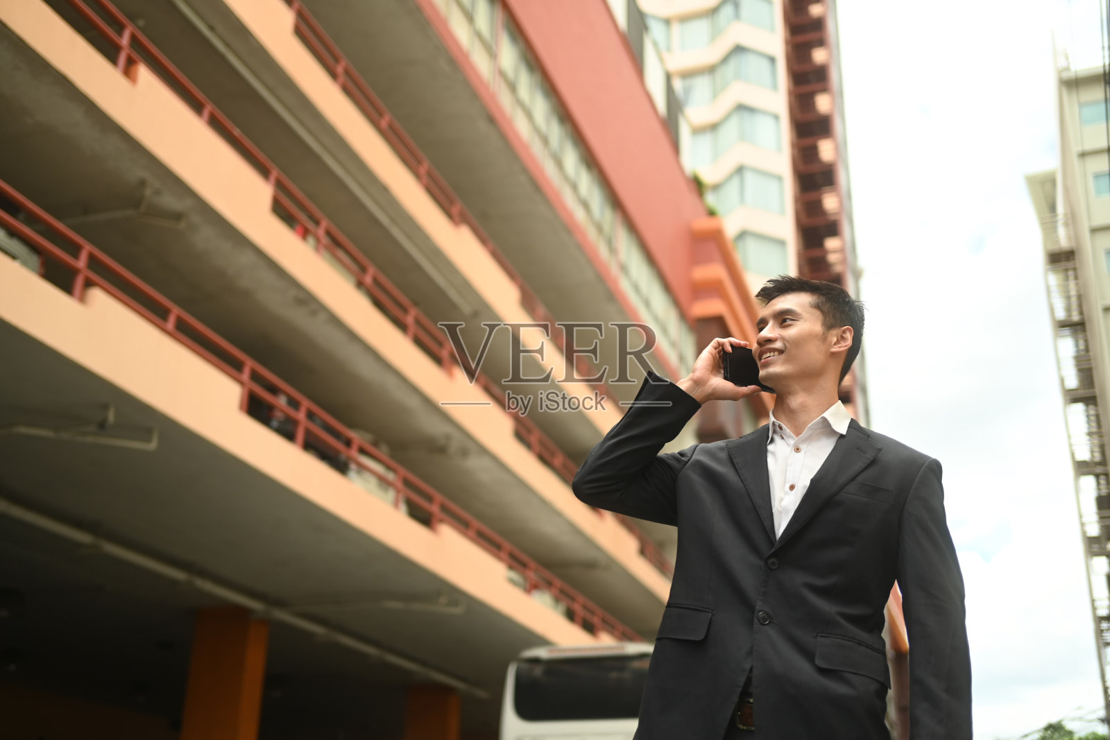 低角度观看正在打电话的优雅商人站在城市街道上看向别处照片摄影图片