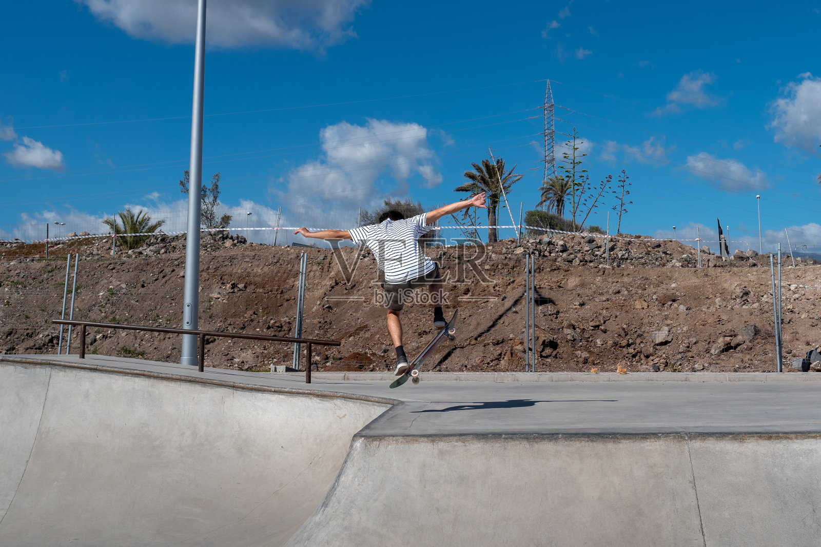 在一个阳光明媚的日子里，一个穿着短裤溜冰鞋的年轻人在溜冰公园里滑冰照片摄影图片