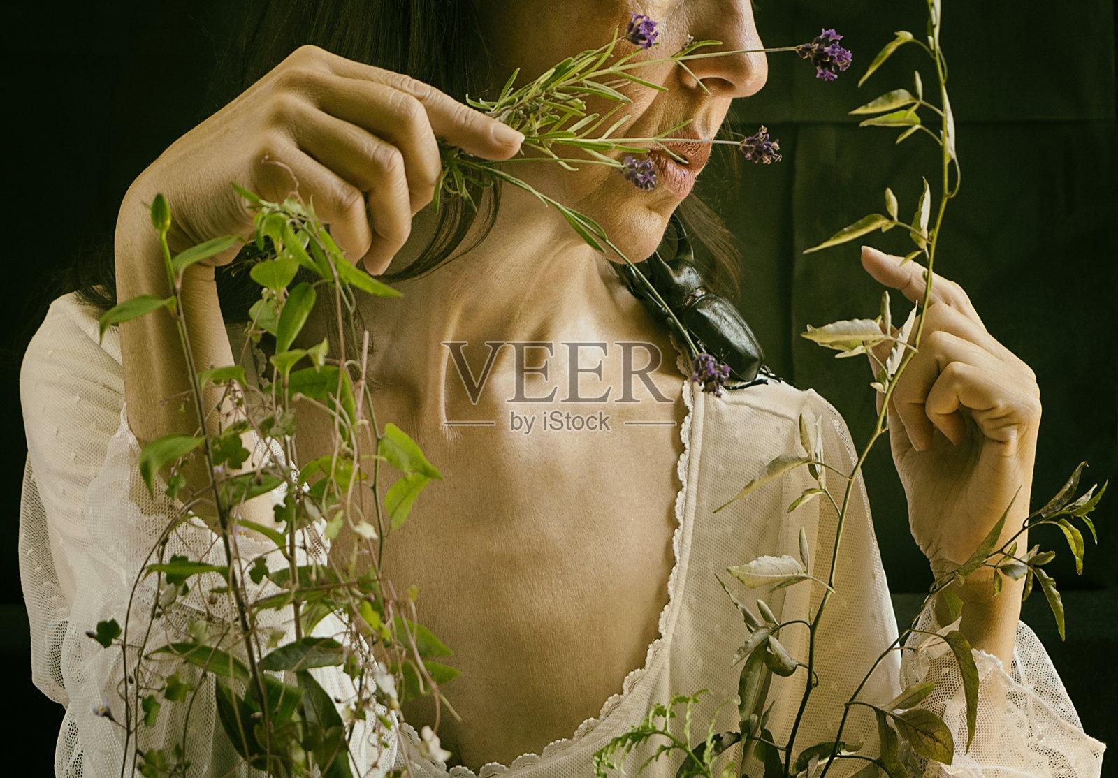 穿着白色浪漫礼服的女人坐在那里，腿上放着一个装满植物和鲜花的箱子照片摄影图片