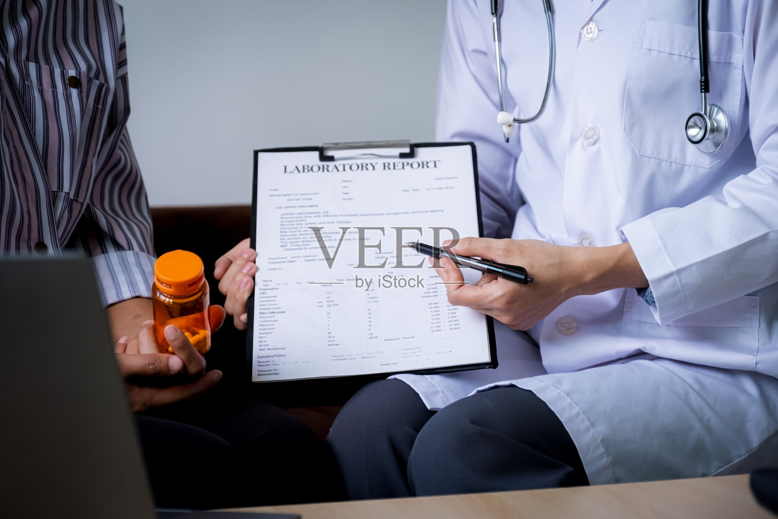 医生在家里的沙发上向病人解释药瓶，并报告健康检查结果，医疗检查的概念照片摄影图片