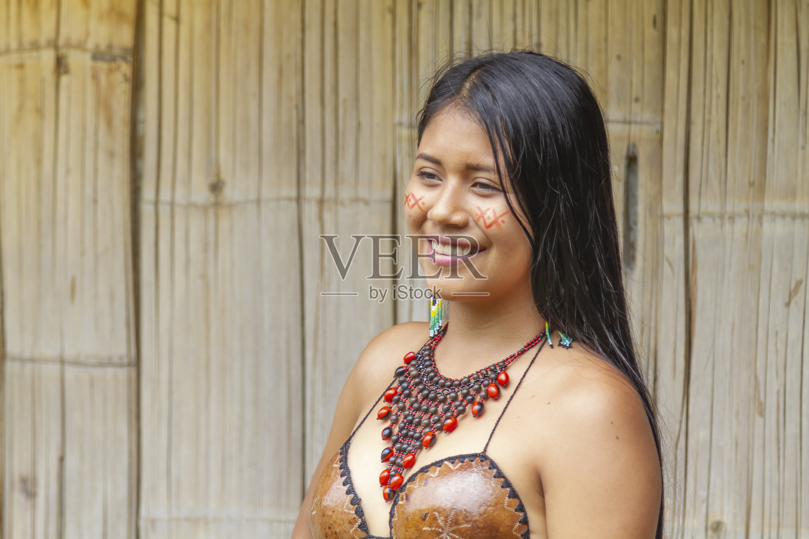 年轻美丽的土著女性肖像，身着部落传统服装，在阳光明媚的日子里在雨林中的村庄拍摄。基奇瓦部落照片摄影图片