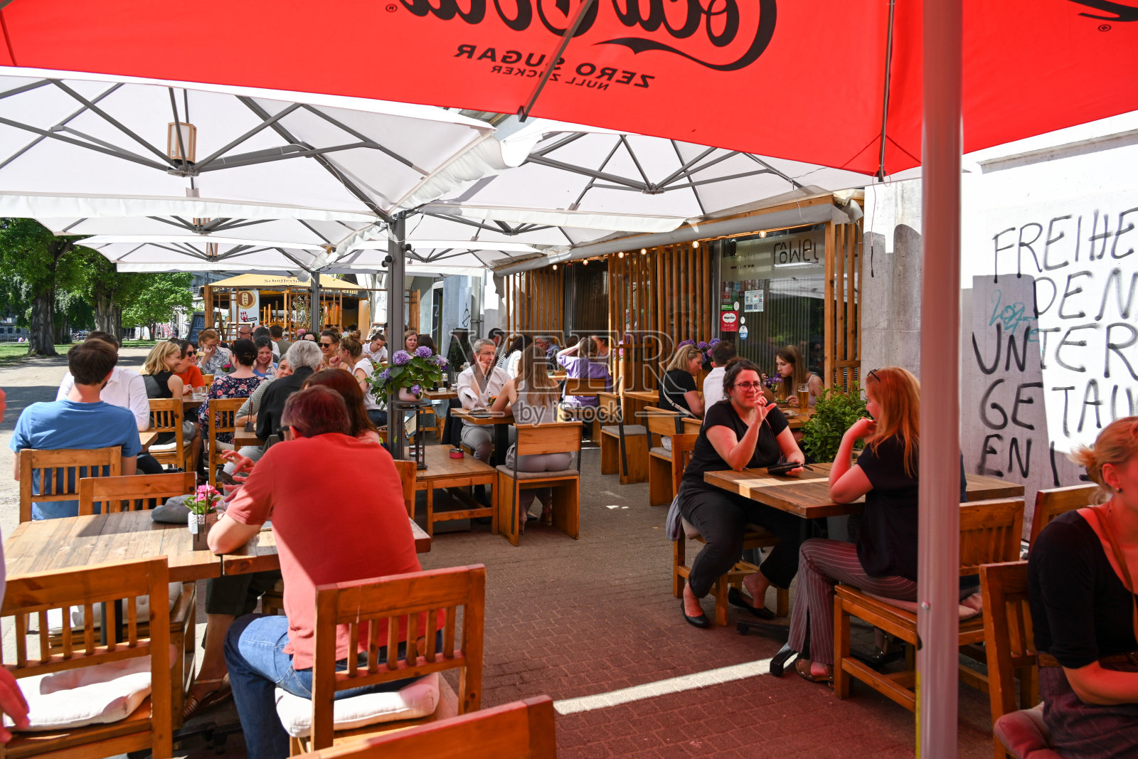 游客和当地人在柏林米特博物馆岛附近的詹姆斯-西蒙公园的花园餐厅里享受阳光。照片摄影图片