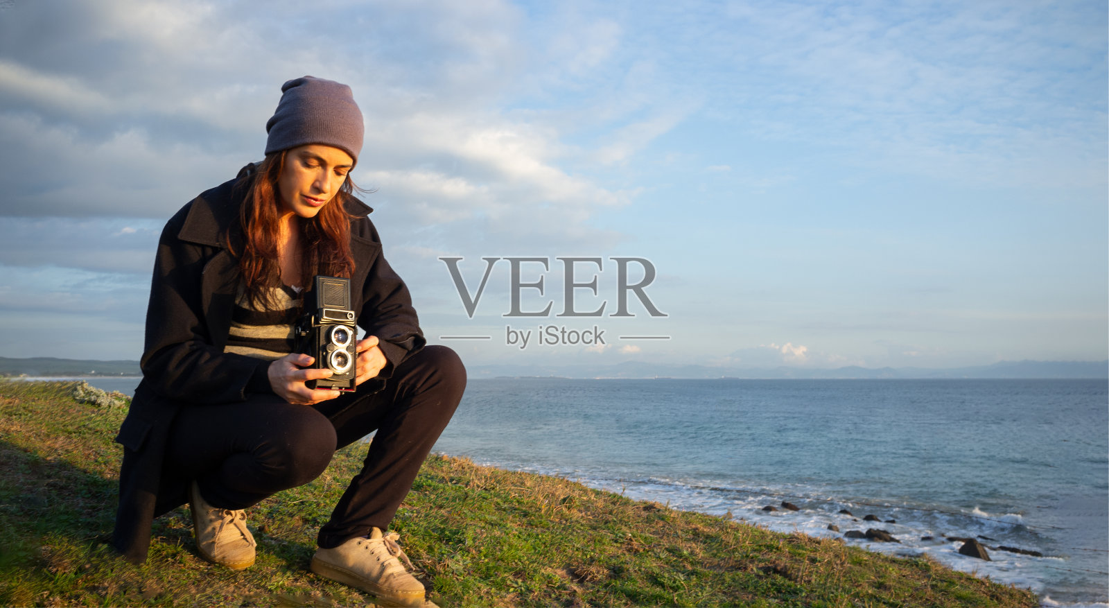 一名女子用一台老式6x6相机拍摄海岸风景。带有复制空间照片摄影图片