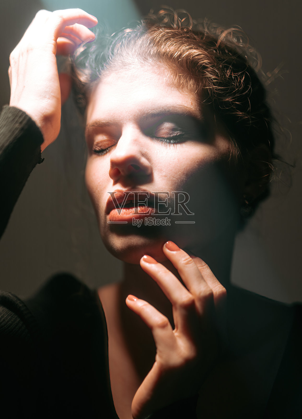 梦幻般的女人闭着眼睛在工作室的灯光下抚摸着头发照片摄影图片