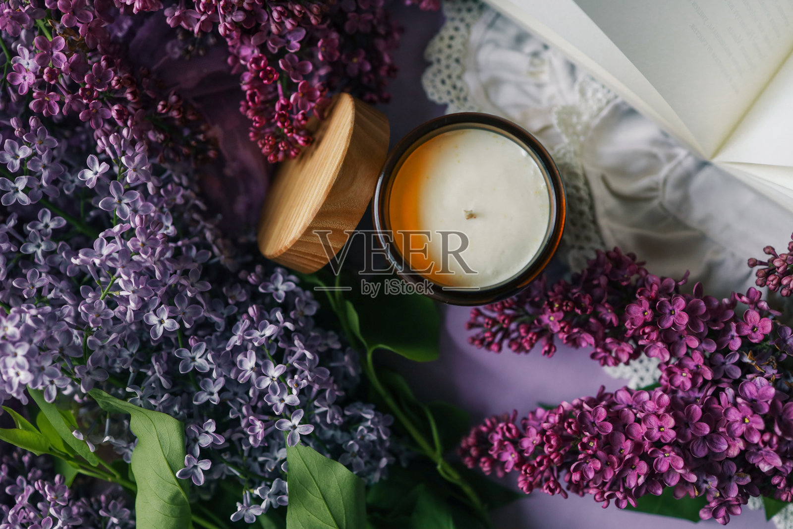 燃烧的蜡烛，一束紫丁香和打开的书，春天的审美照片照片摄影图片