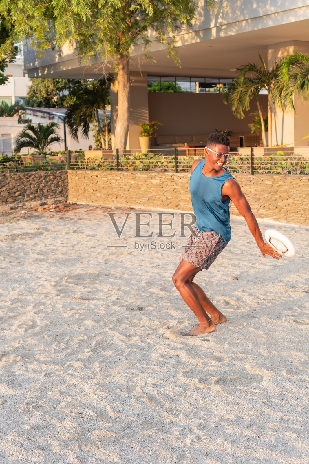 日落时分，男子在沙滩上玩飞盘照片摄影图片