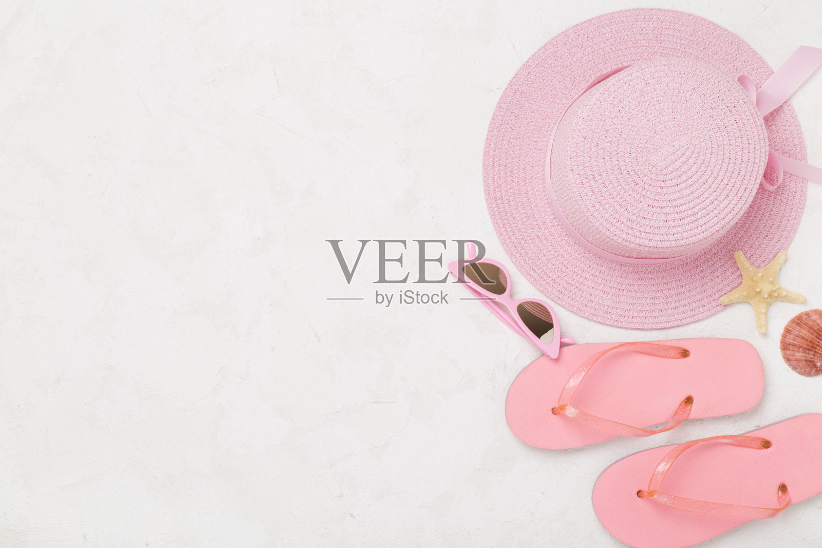 混凝土背景上平躺着粉红色的夏装。假期的概念照片摄影图片