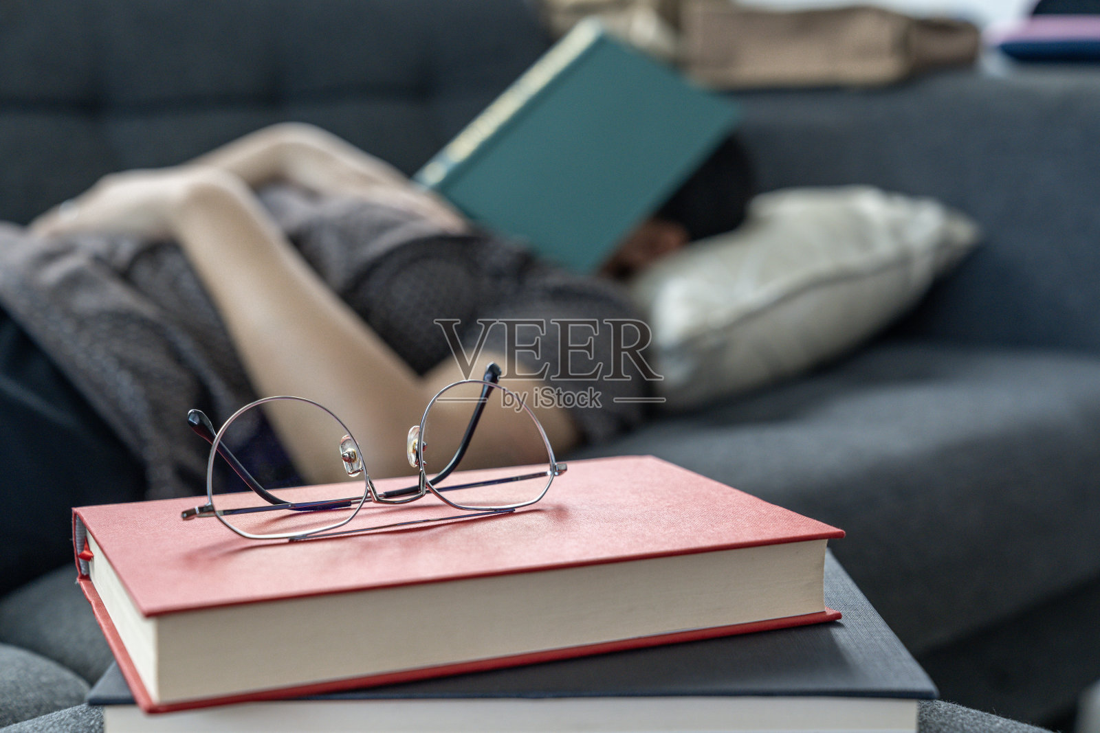 一个年轻女子在家里的沙发上看书睡着了照片摄影图片