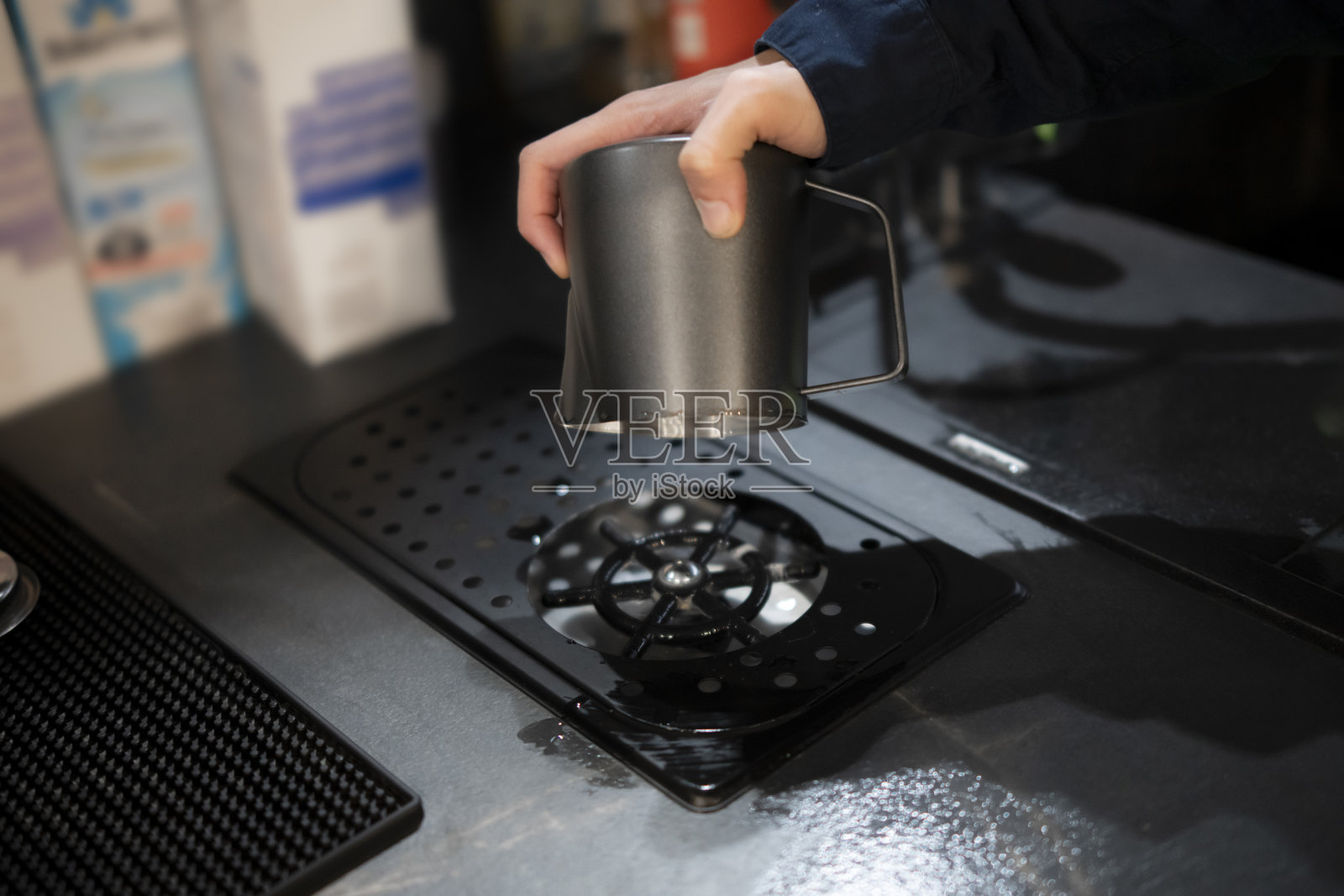 夜间，男子在酒吧柜台的自动洗衣机上拿着一只金属杯照片摄影图片