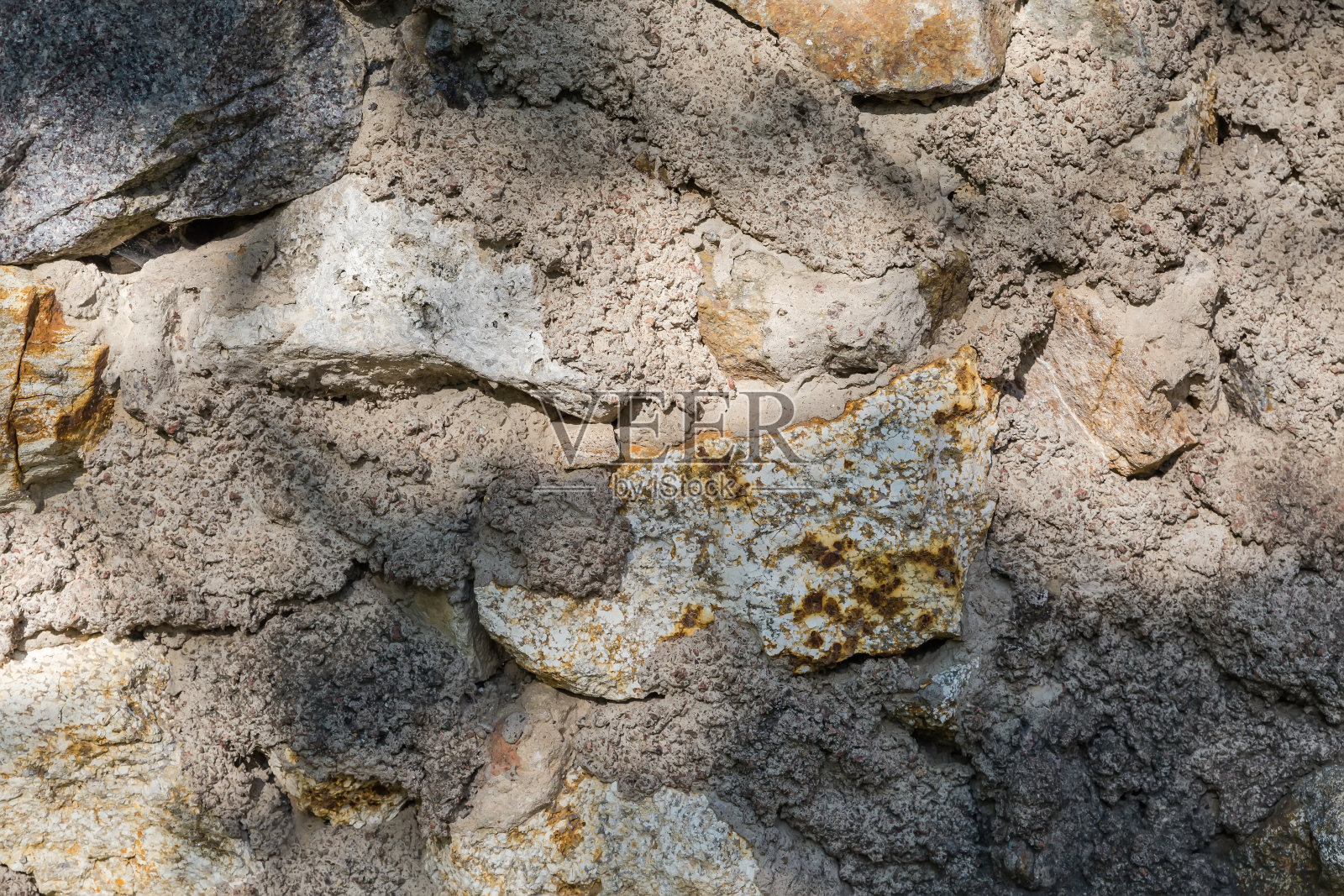 阳光明媚的日子里，旧石头和混凝土墙的碎片照片摄影图片