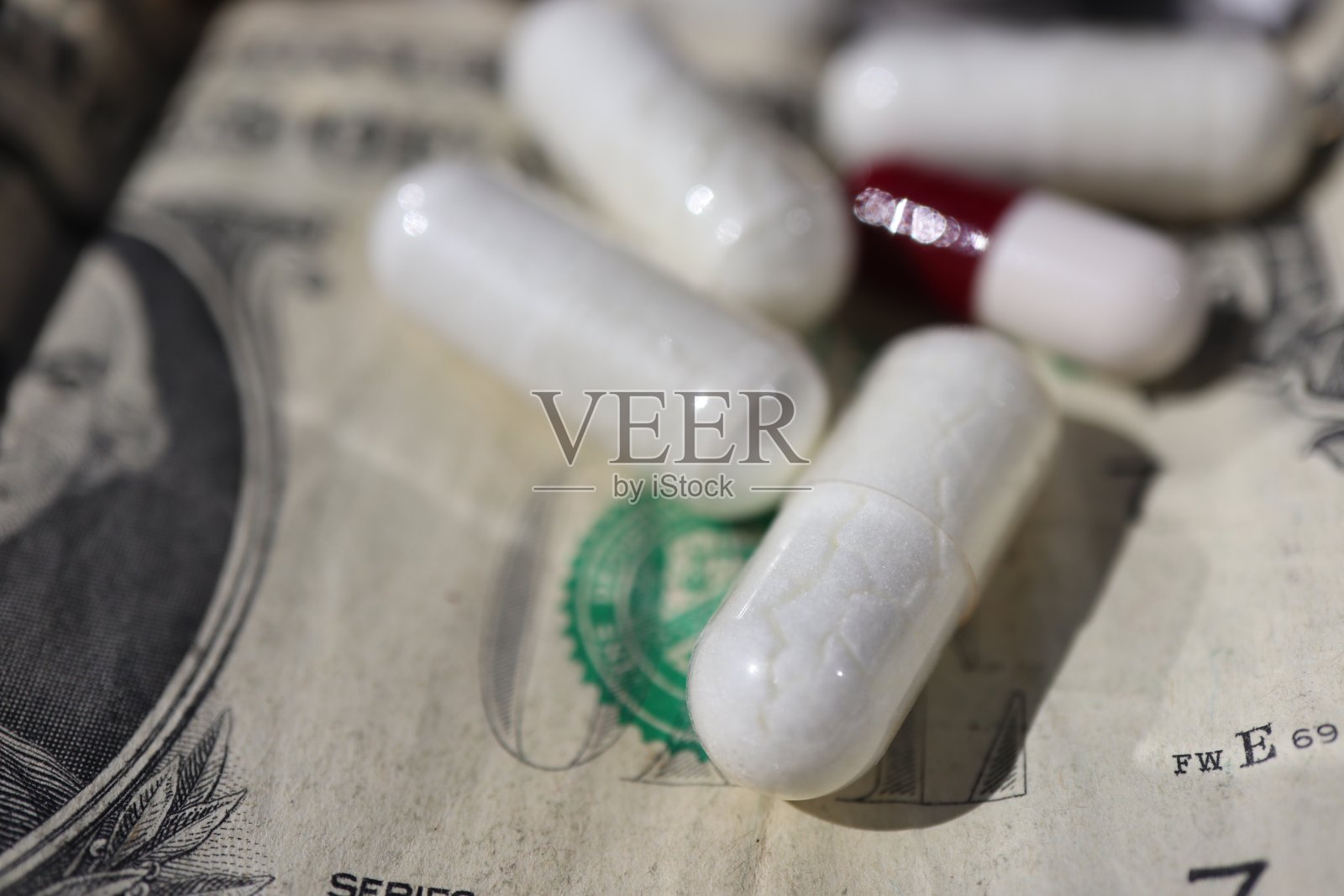 白色和红色的胶囊药丸从白色的塑料瓶容器中溢出。照片摄影图片