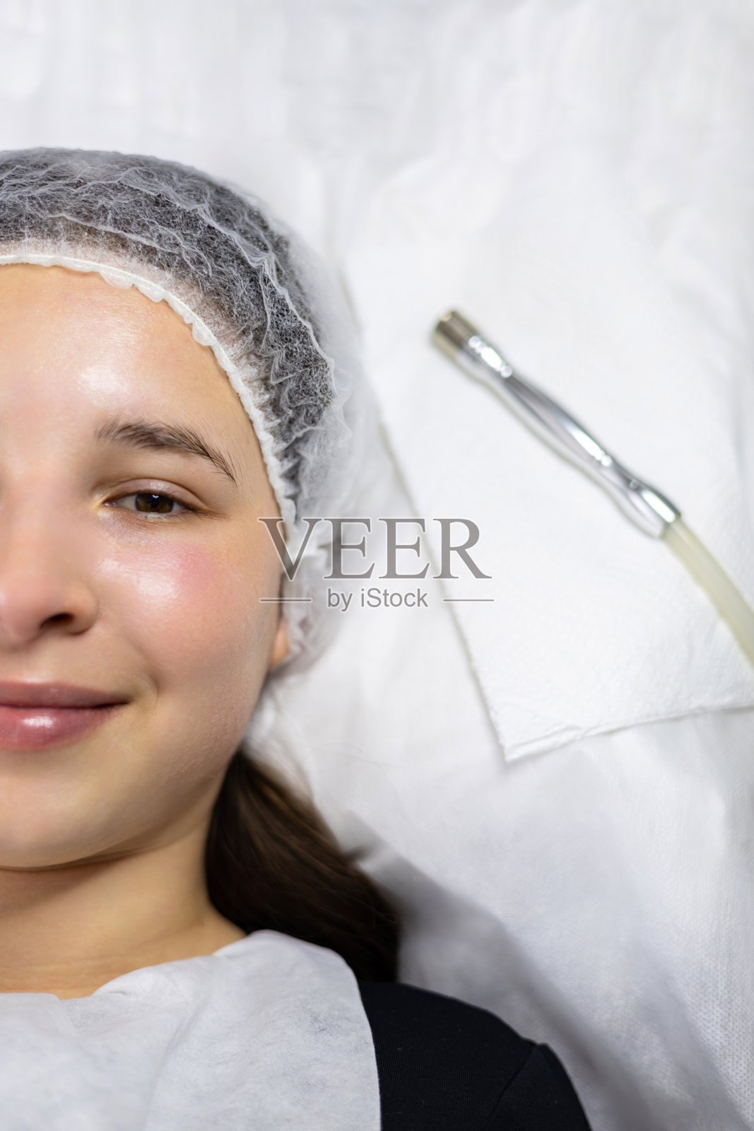 从上图来看，一位年轻女性在用真皮笔进行美容微磨皮手术后，躺在真皮笔旁边的手术台上。照片摄影图片