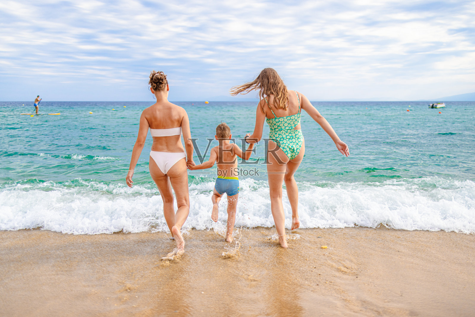 难以辨认的年轻白人兄弟姐妹手牵着手奔向大海照片摄影图片