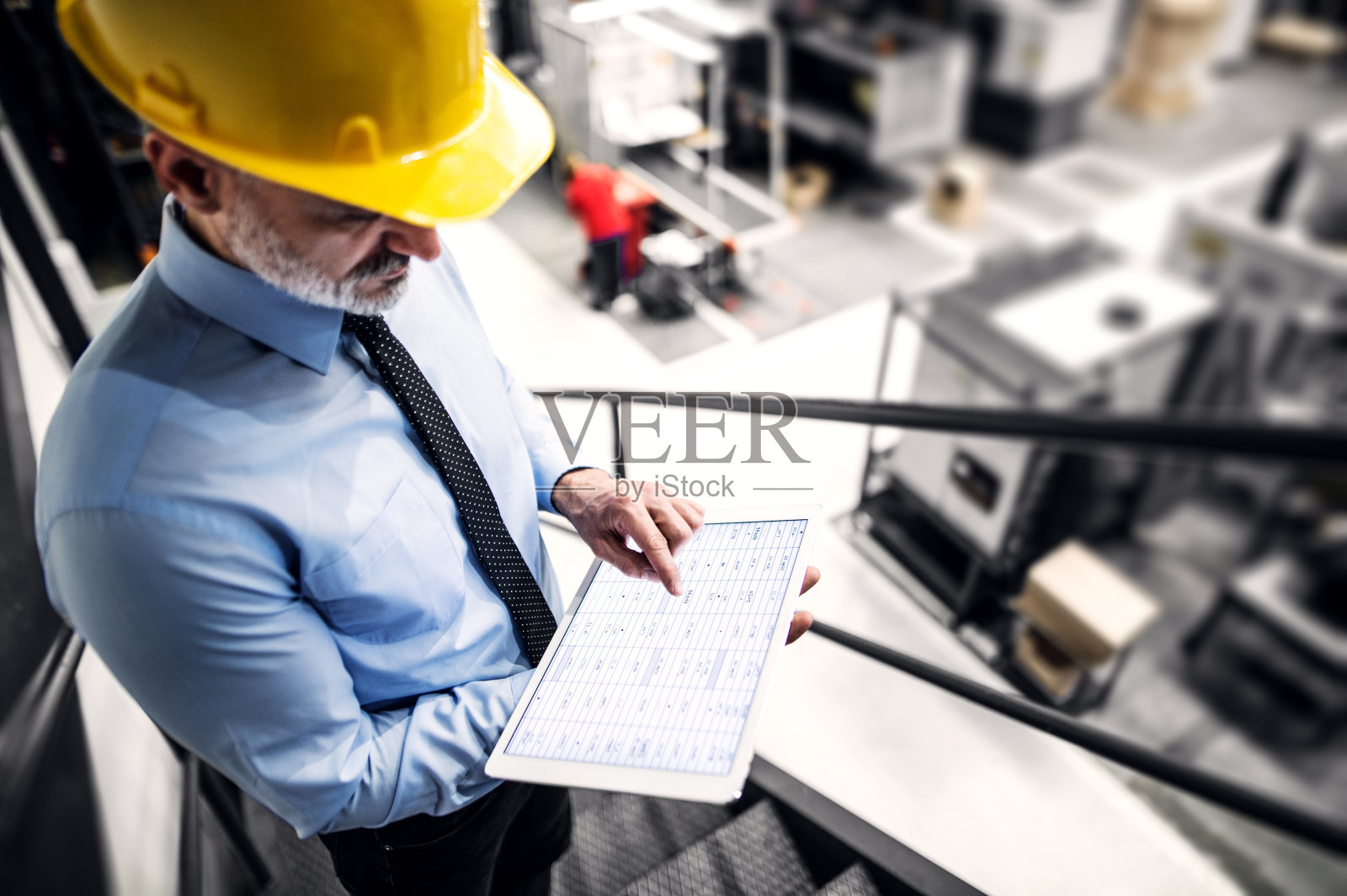 项目经理站在现代工业工厂里，手里拿着写字板。制造工厂配备机器人，机械臂和自动化。仓库中产品和物料的存放。照片摄影图片