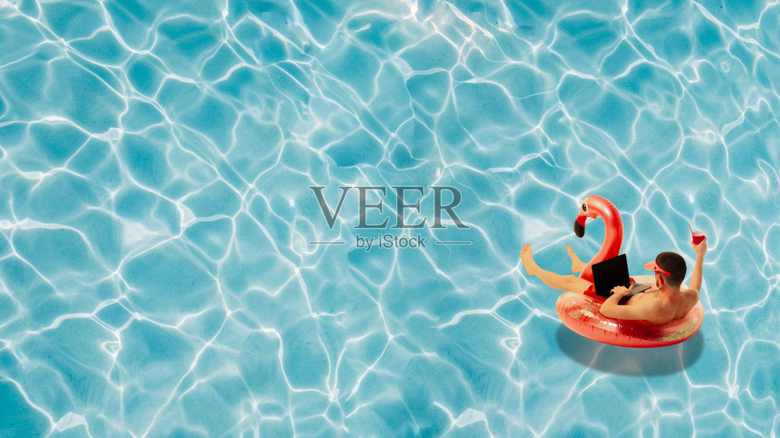 当代艺术拼贴。男子在游泳火烈鸟圈漂浮在游泳池和网上工作，喝鸡尾酒。抽象的艺术作品。照片摄影图片