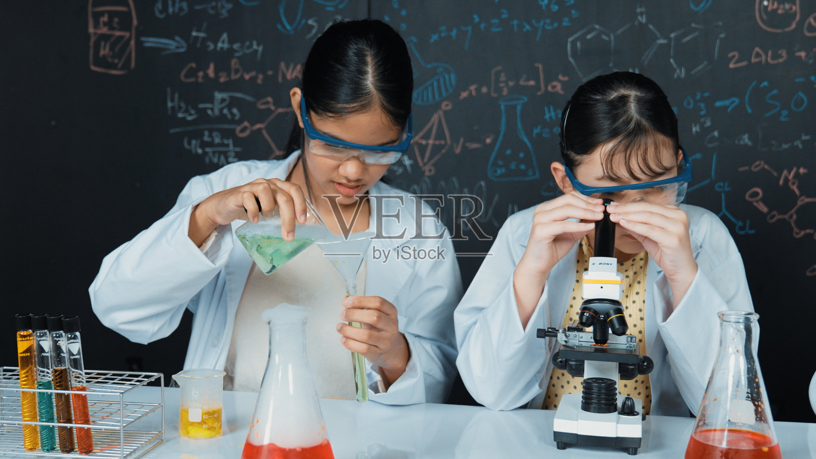 年轻学生在试管中倒样品做实验。启迪。照片摄影图片