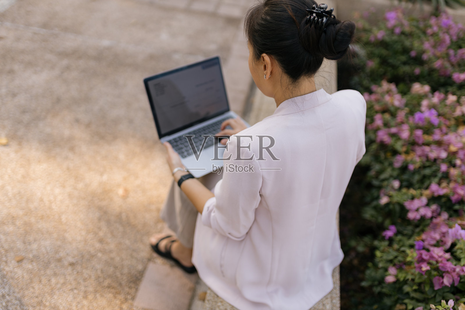 一个女商人在公园里使用笔记本电脑的后视图。照片摄影图片