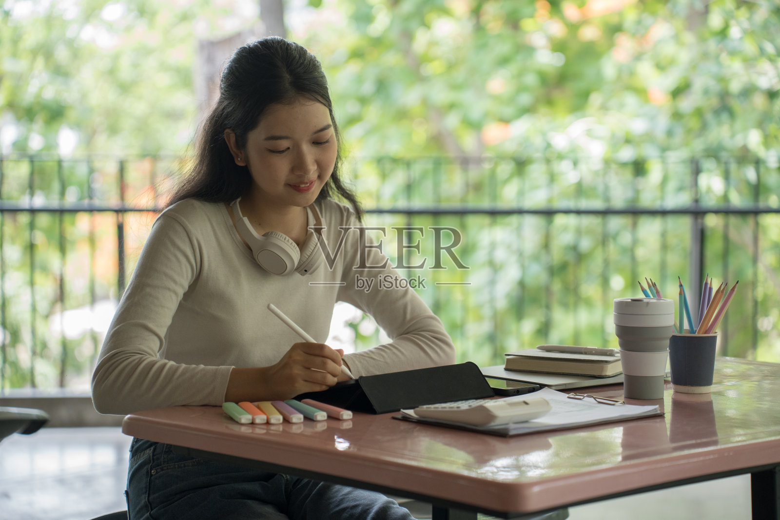 年轻的亚洲女学生在看完视频后用平板电脑记笔记和做作业，在大学的网络课堂上学习和学习商业教育知识照片摄影图片
