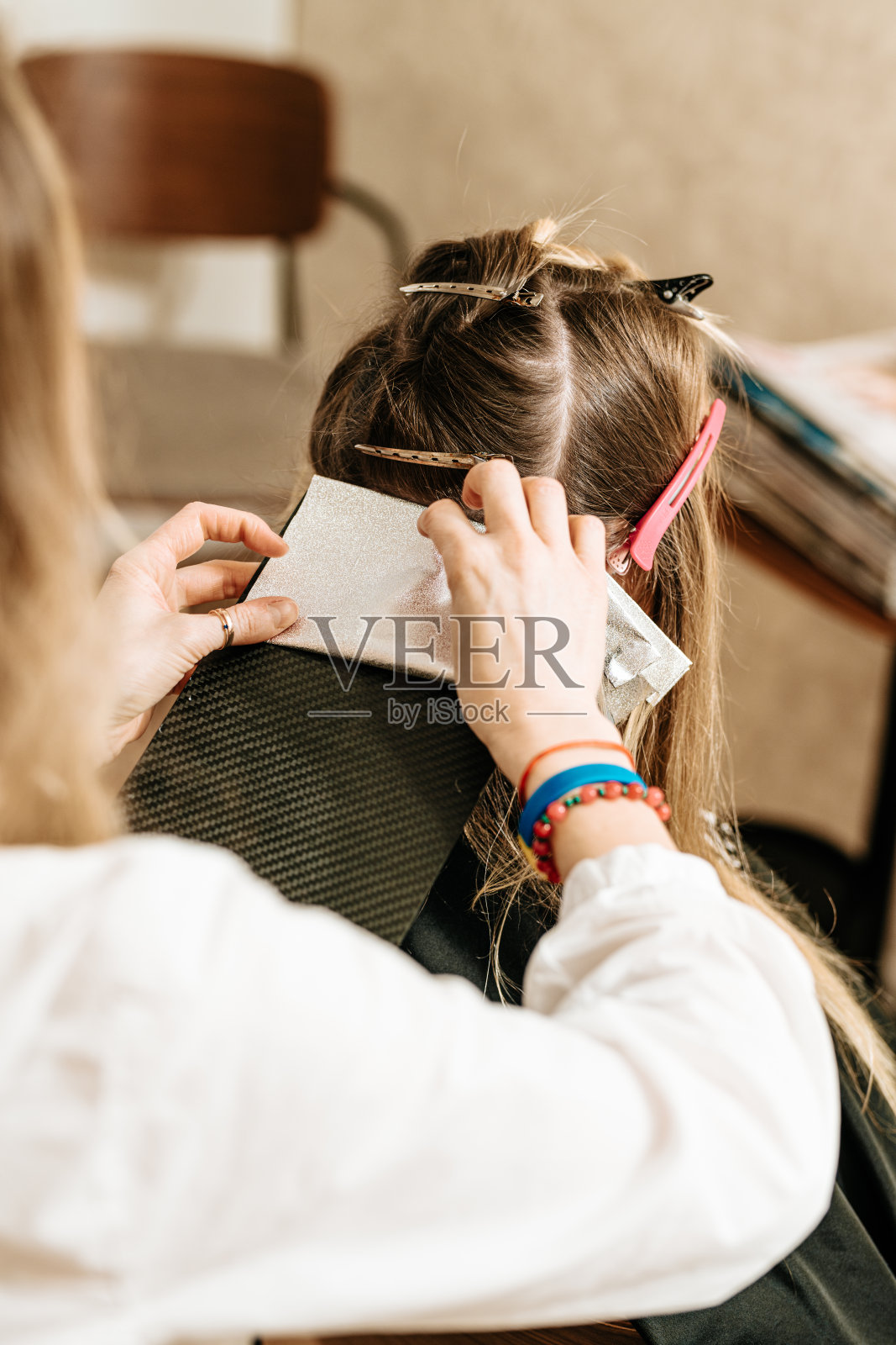 发型师用铝箔给发廊里的妇女染染发剂照片摄影图片