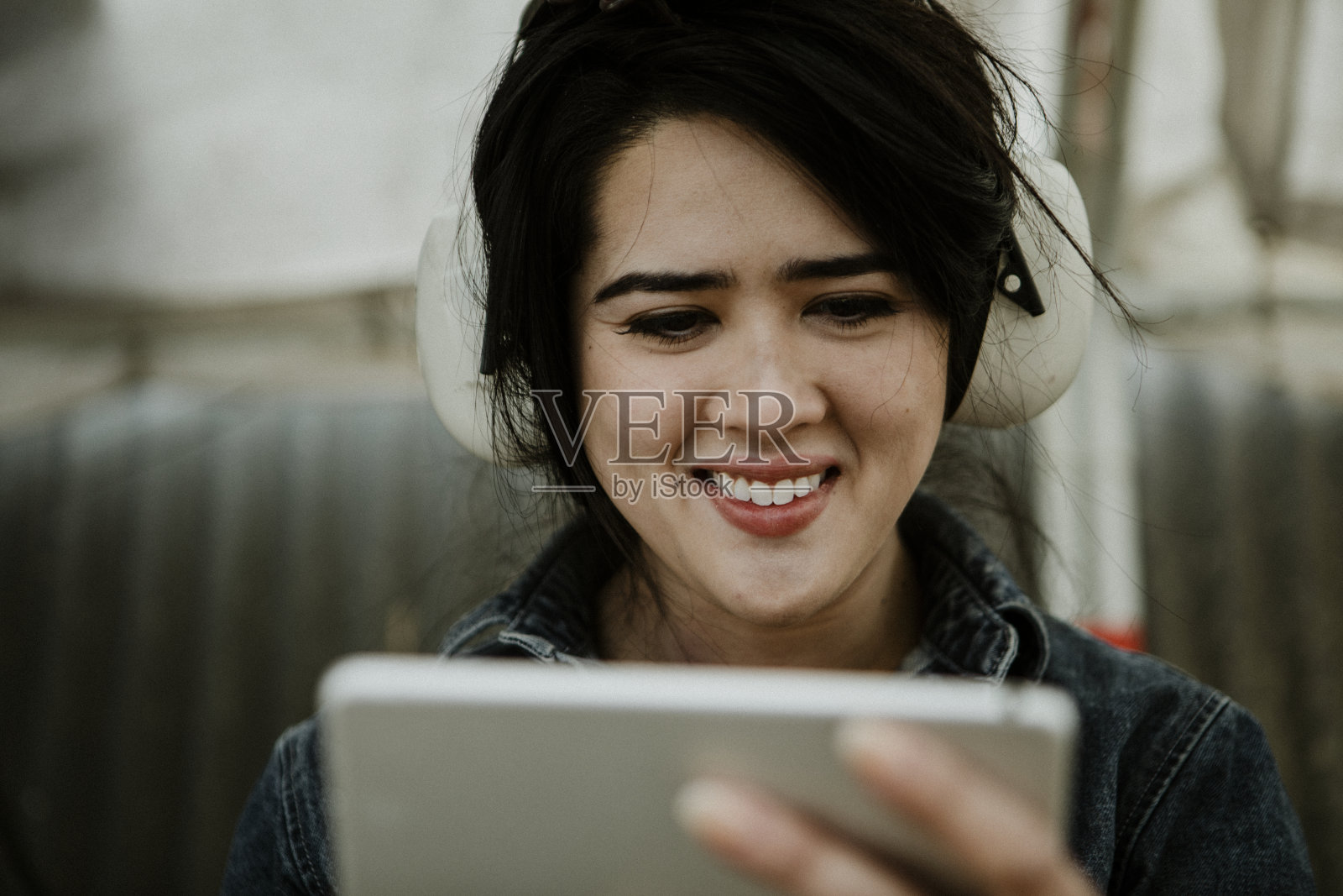 快乐的女木匠戴着保护耳机在车间使用平板电脑照片摄影图片