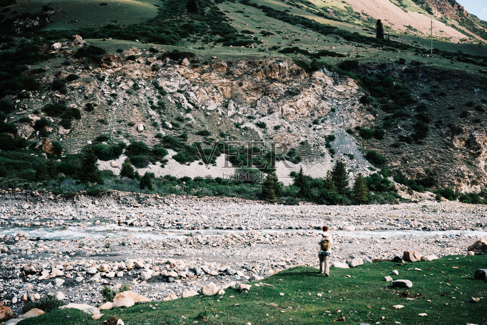 女游客走在山谷的河岸上。Barskoon河照片摄影图片