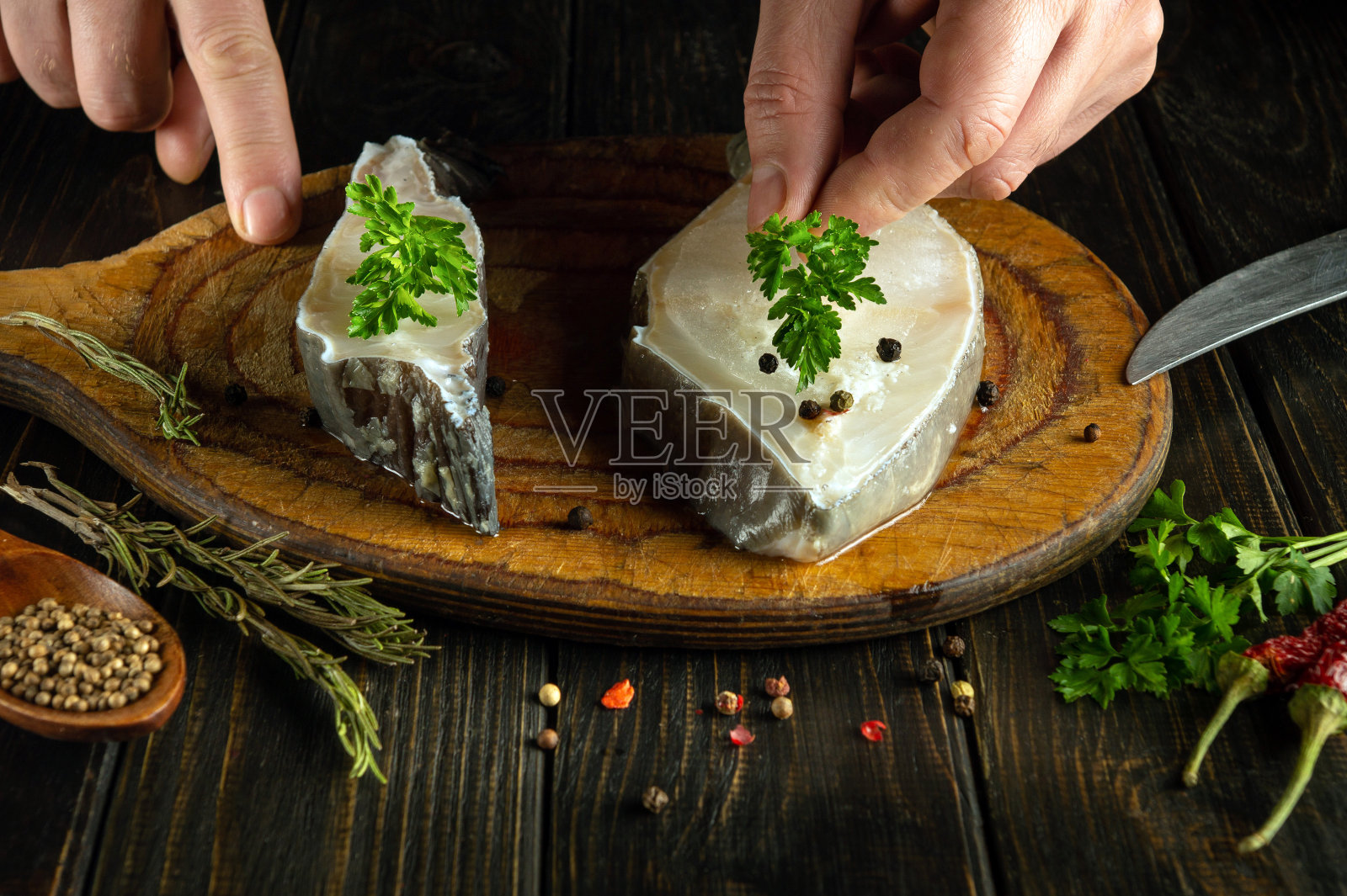 厨师在煎鱼前用手往鱼里加香菜的特写。餐馆里美味的鱼的概念照片摄影图片