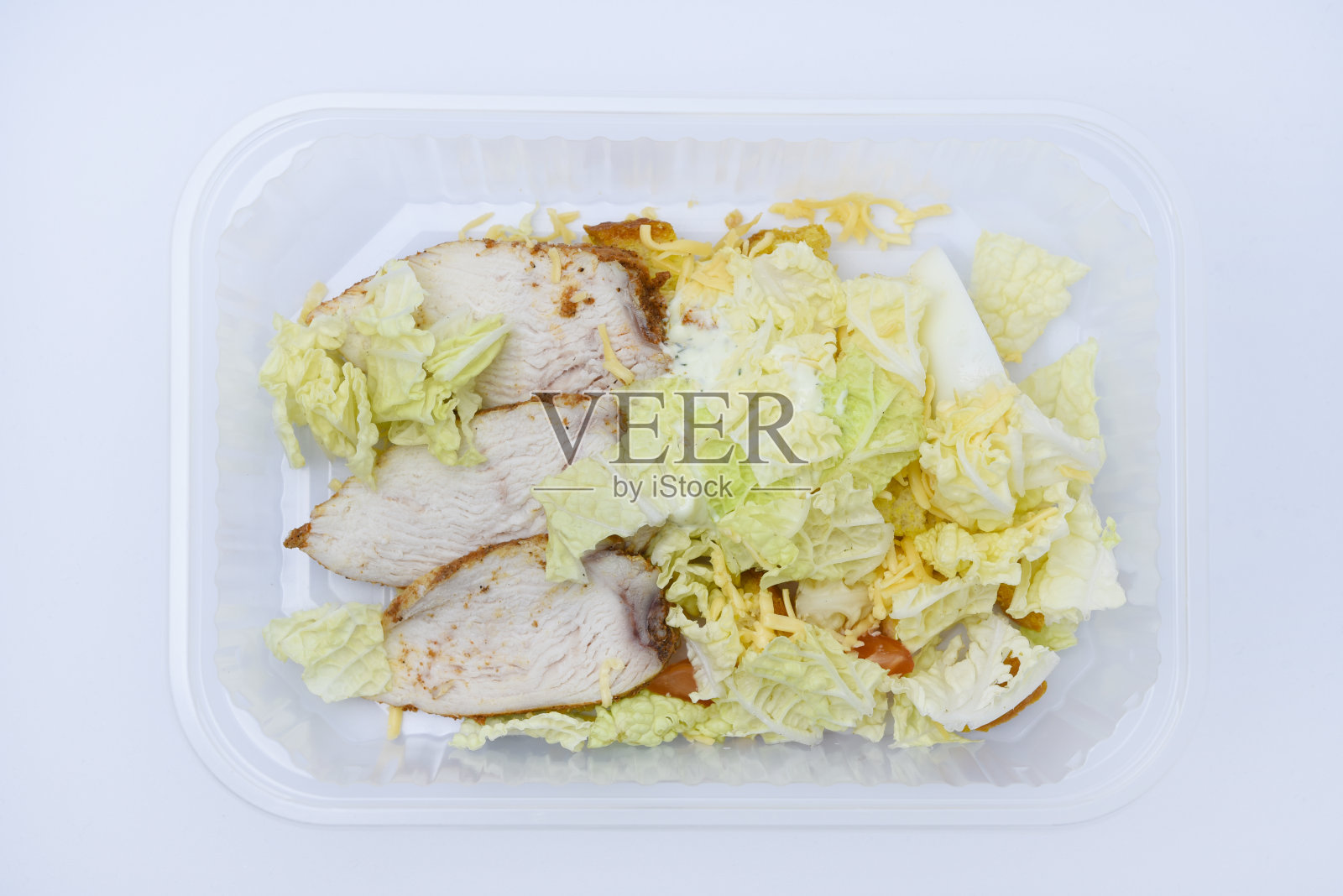 用塑料容器盛着肉和蔬菜的凯撒沙拉。清淡的早餐。照片摄影图片