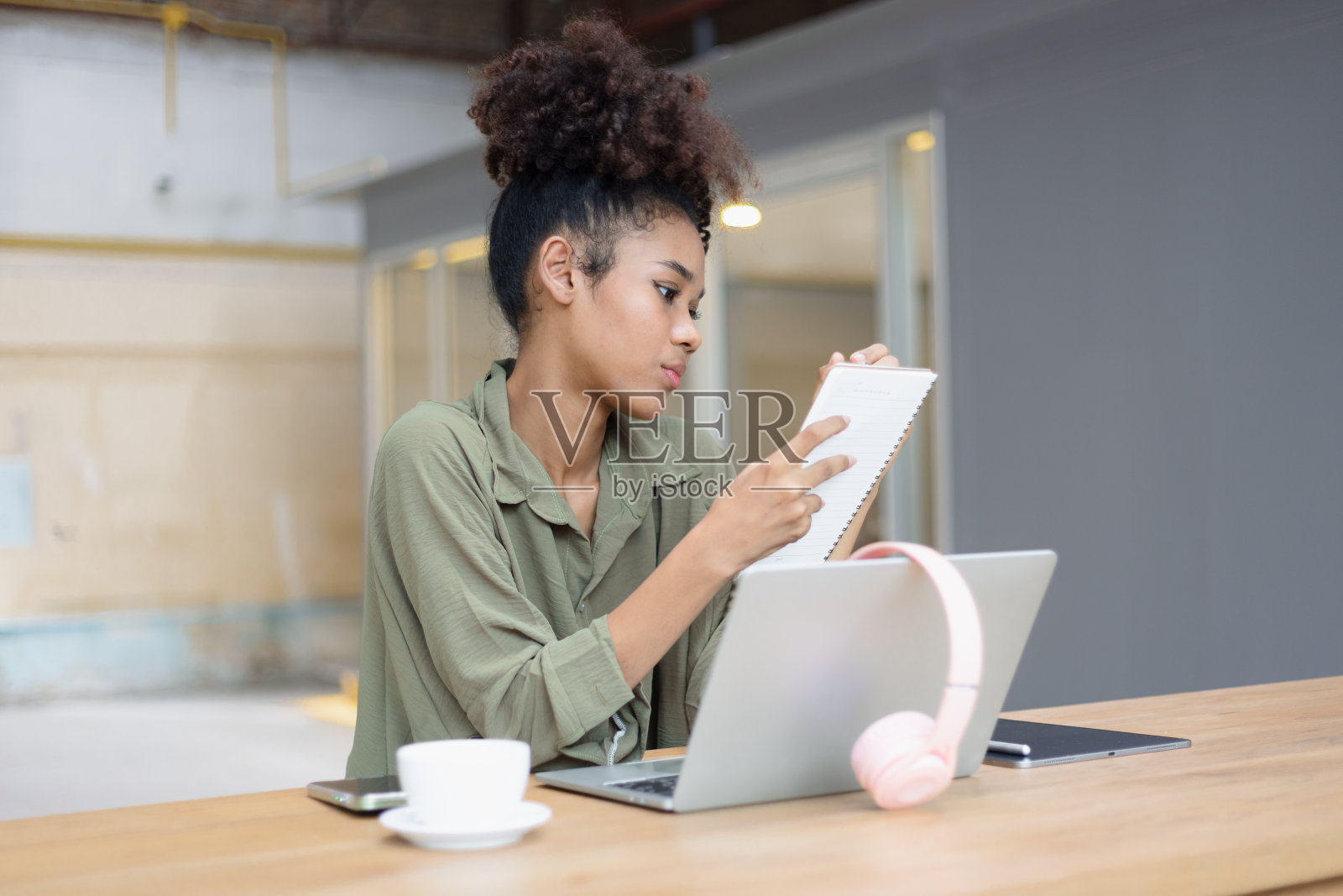 非裔美国女性自由职业者使用平板电脑和笔记本电脑在办公桌上工作。照片摄影图片