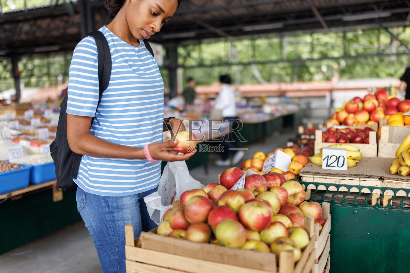 年轻的女顾客在市场摊位上挑选新鲜水果照片摄影图片