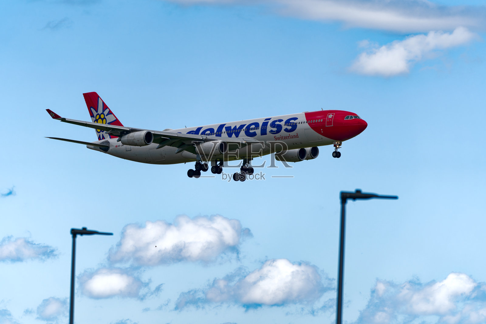 雪绒花航空公司的白、红、蓝三色瑞士飞机在瑞士机场最后进场时的侧视图。照片摄影图片