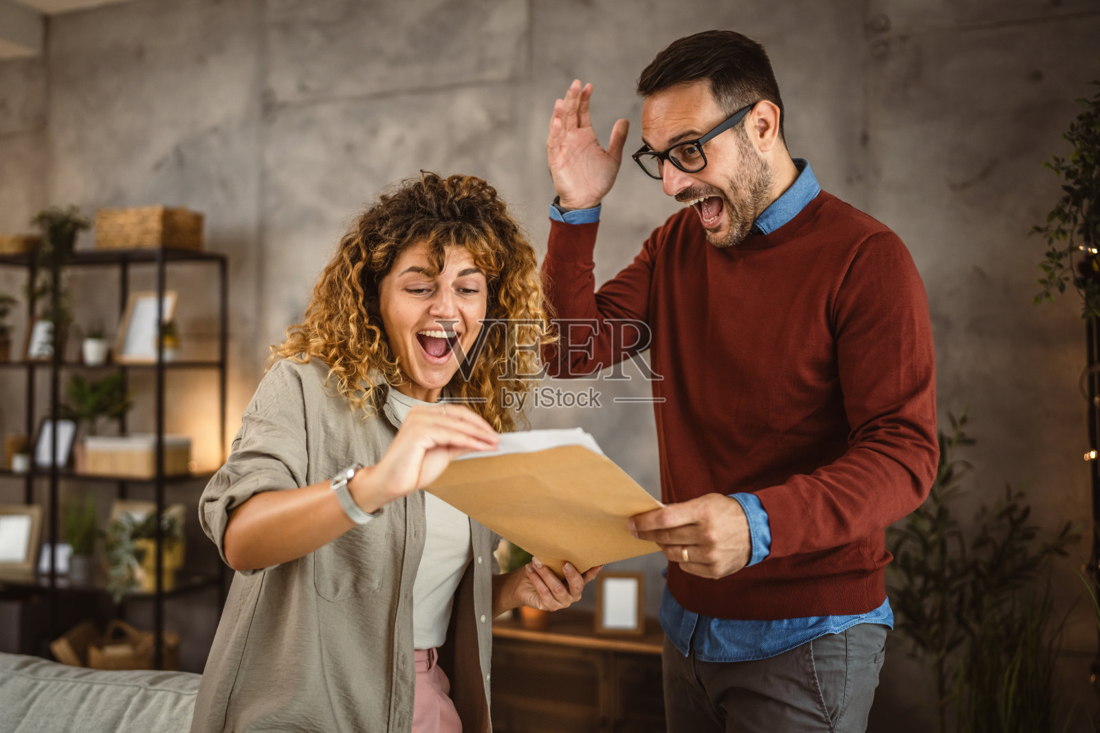 幸福的夫妇在家里读着信封里的喜讯照片摄影图片
