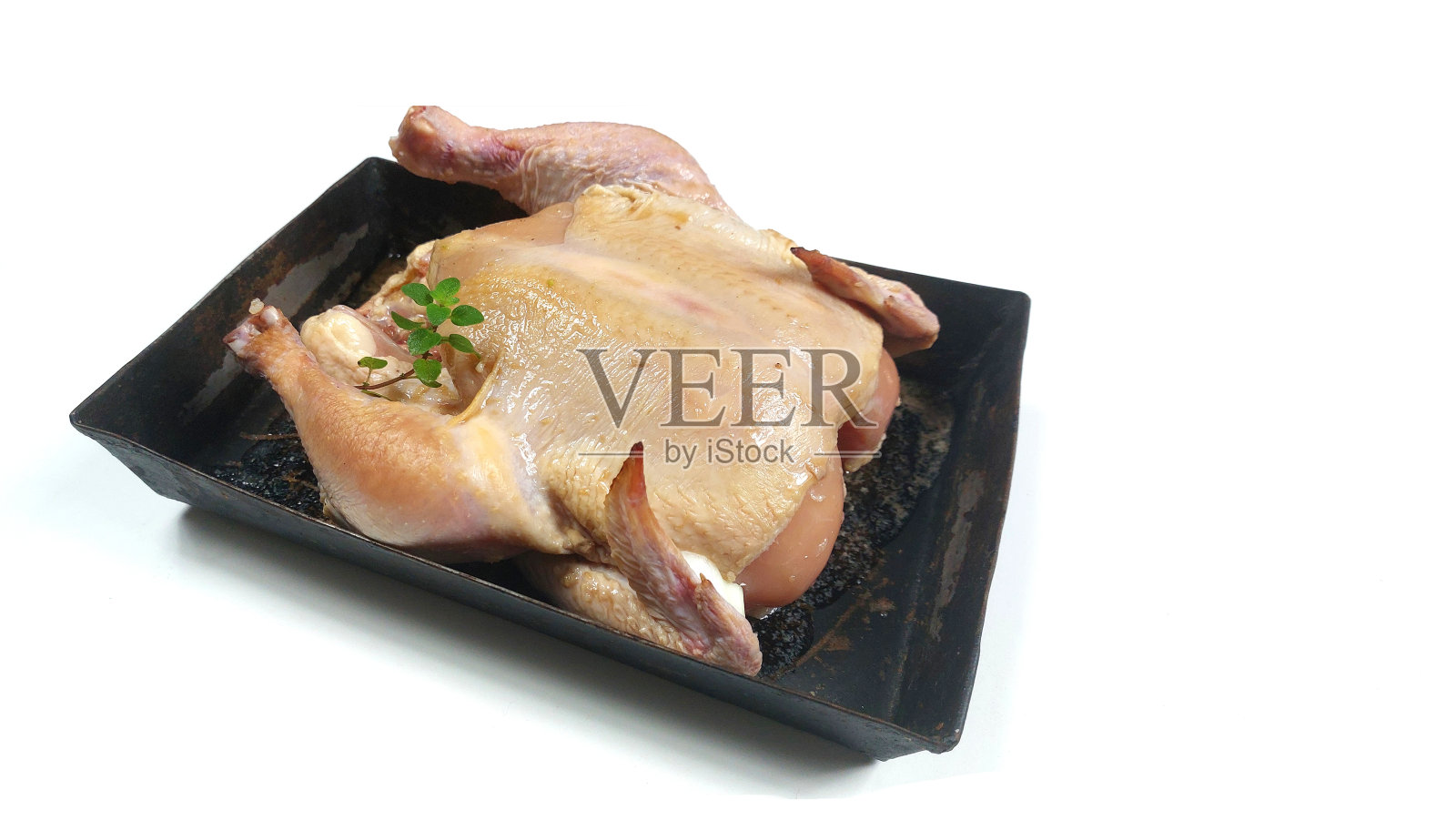 整只生鸡肉放在黑色盘子里照片摄影图片